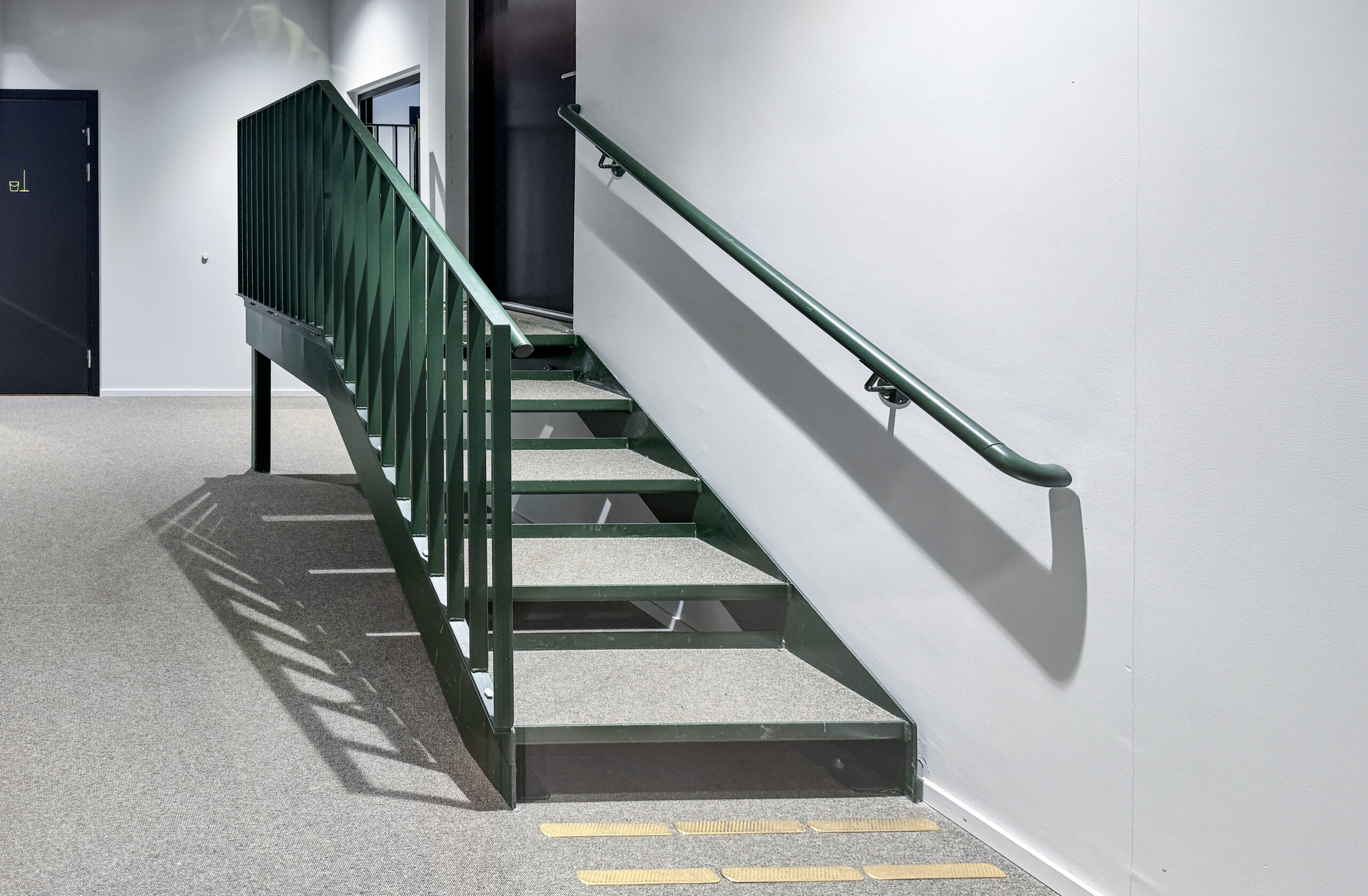 Innvendig ståltrapp med grønt rekkverk levert av EMV Construction